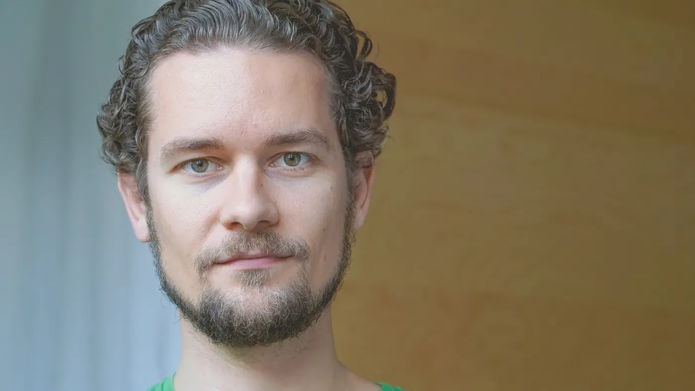 Porträtt av en man med fullt hår mot neutral bakgrund